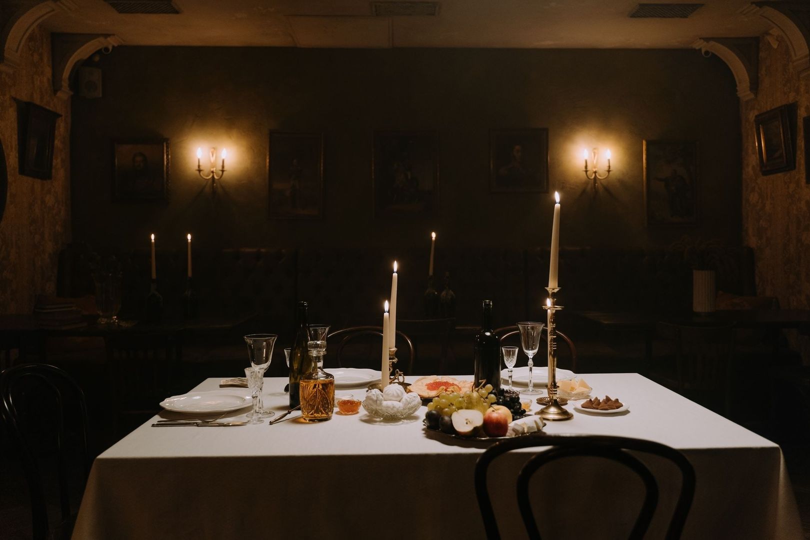 Candlelit vintage dining table in a dark, art-filled supper club room