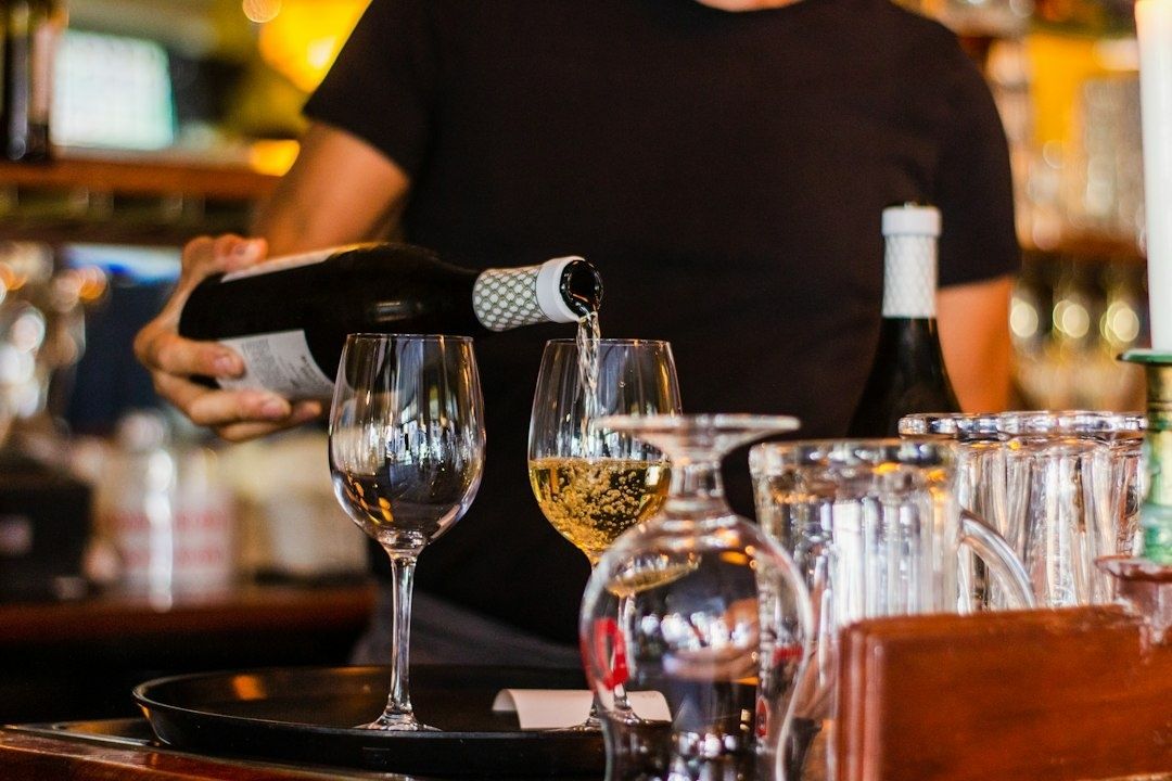 Server pours wine into a glass at a busy restaurant bar