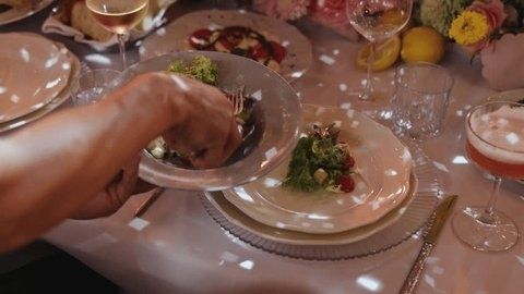 Server placing food on a plated course at an elegantly set table